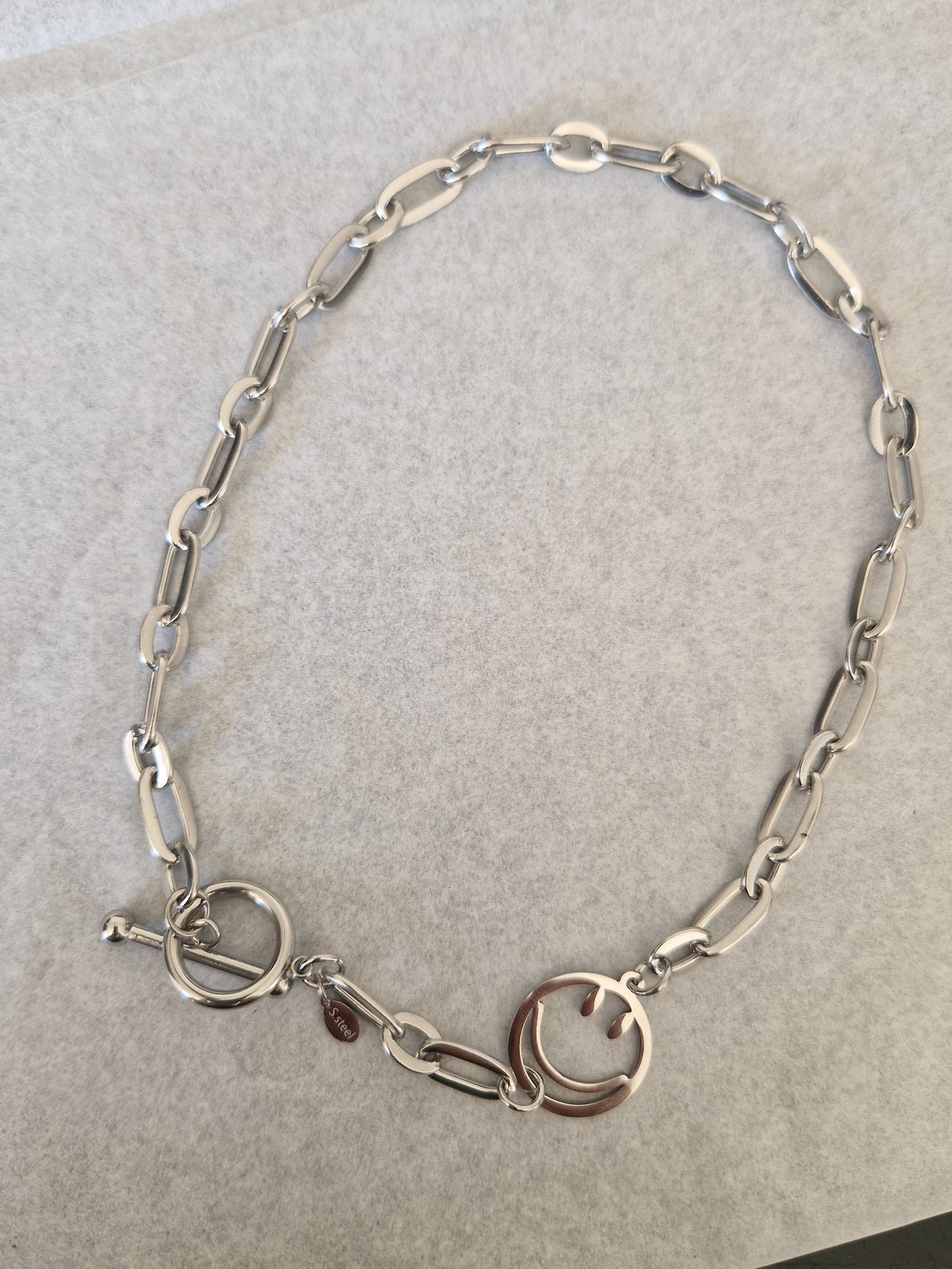 Collier ras-de-cou 'Joie' en acier inoxydable argenté avec pendentif smiley souriant et chaîne moderne de 36 cm. Design simple et ludique.